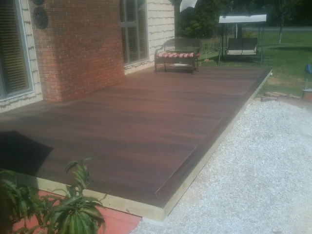 Freshly stained wood deck built against a brick home in Colbert
