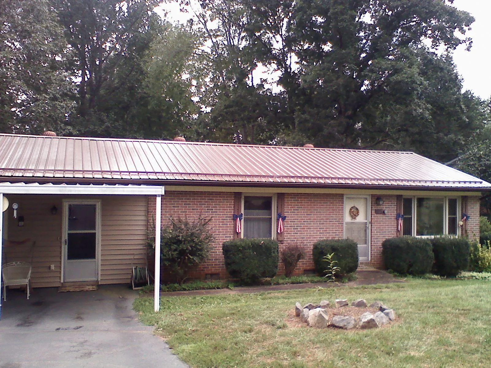 Bronze metal roof and carport on a brick ranch home — Roof Repair work by our crew in Colbert